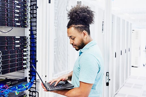 Man on a laptop in a room full of servers